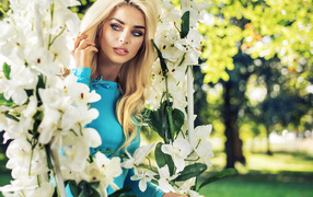 Beautiful blonde near a swing with white flowers
