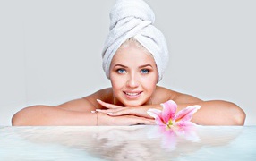 Красивая голубоглазая женщина в тюрбане с полотенца расслабляется в SPA