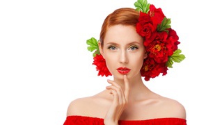 Красивая яркая девушка с красными цветами в волосах на белом фоне