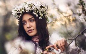 Красивая брюнетка с венком из цветов вишни на голове