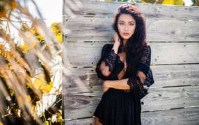 Красивая девушка в черном платье у стены 