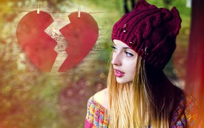 Красивая девушка в вязаной шапке на фоне разбитого сердца