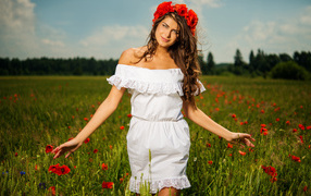Beautiful girl in a white dress with a wreath of red poppies on her head