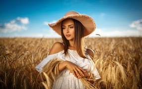 Красивая девушка в белом платье с колосьями пшеницы