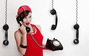 Красивая девушка в красном с черным старым телефоном в руках
