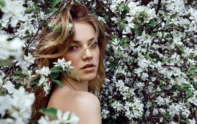 Красивая девушка в ветках цветущей яблони 