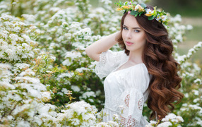 Beautiful girl in white dress among blooming white flowers