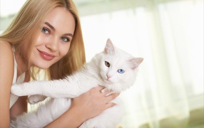 Beautiful girl with a white cat in her hands