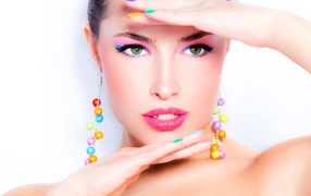 Красивая девушка с ярким макияжем и разноцветным маникюром на ногтях