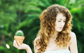 Beautiful girl with closed eyes with a cactus in hand