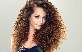 Красивая девушка с длинными волнистыми волосами на сером фоне