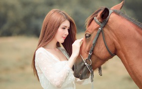 Красивая длинноволосая азиатка гладит лошадь