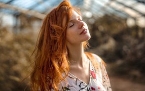 Beautiful red-haired girl basking in the sun