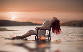 Красивая рыжеволосая девушка на стуле в воде
