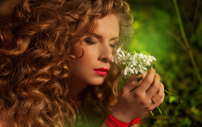 Красивая рыжеволосая девушка с букетом подснежников в руках