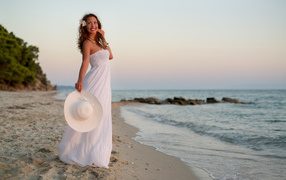 Красивая улыбающаяся девушка в белом платье на побережье