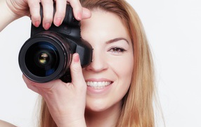 Красивая улыбающаяся девушка с фотоаппаратом