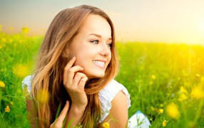 Красивая улыбающаяся молодая девушка лежит в зеленой траве