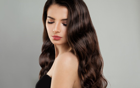 Красивая молодая длинноволосая девушка брюнетка на сером фоне