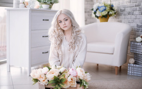 Blonde girl with peonies sitting in the room