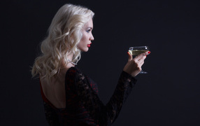 Blonde with a martini glass in hand against a gray background