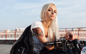 Брутальная блондинка с татуировкой на руке на мотоцикле 