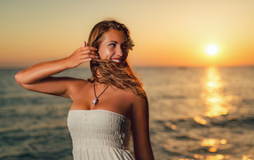 Charming smiling girl with brown-haired woman on the beach at sunset