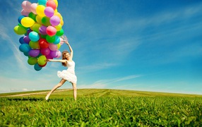 Веселая девушка в белом платье с разноцветными воздушными шариками