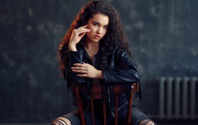 Модная красивая девушка в черное кожаной куртке сидит на стуле
