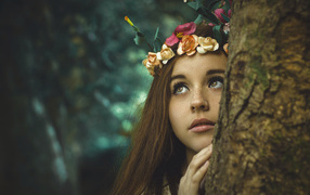 Girl with a wreath on her head near a tree