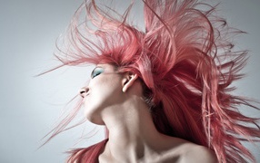 Девушка с распущенными розовыми волосами на сером фоне