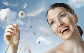 Счастливая девушка с одуванчиком в руке 