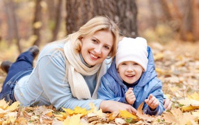 Mother and son lie on leaves in autumn