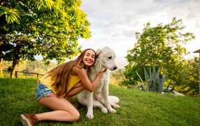 Smiling brown-haired woman with golden retriever on green grass in summer