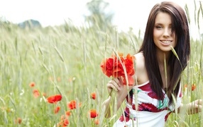 Smiling girl model in a field with red poppies