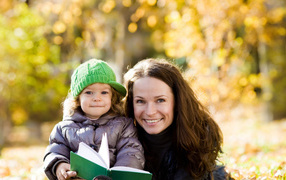 Улыбающаяся девушка с девочкой читают книгу