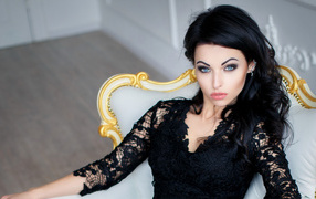 Эффектная брюнетка в черном платье сидит в кресле