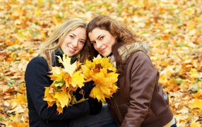 Две красивые девушки с желтыми листьями в руках