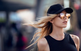 Молодая блондинка в солнечных очках и черной кепке 