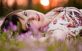 Молодая кареглазая девушка лежит на траве