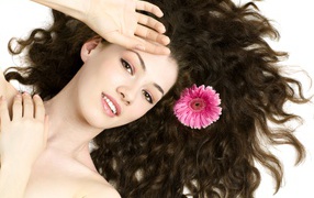 Young brown-haired woman with a pink gerbera flower in her hair