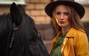 Молодая девушка в черной шляпе с конем 