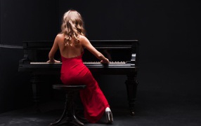 Young girl in a red dress playing the piano