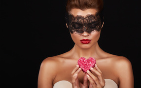 Young girl in black mask with red heart in hands
