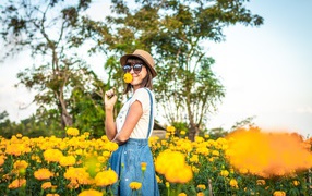 Молодая девушка в солнечных очках в желтых цветах 