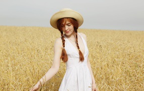 Молодая девушка в белом платье на поле с пшеницей