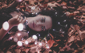 Young girl lies with a garland on yellow leaves