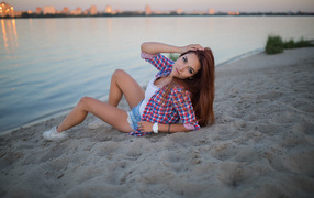 Молодая девушка лежит на песке у реки