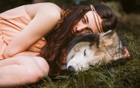 Молодая девушка с собакой породы хаски лежит на траве