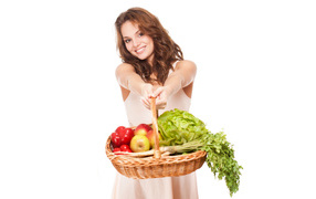 Young girl with basket of vegetables and fruits on a white background